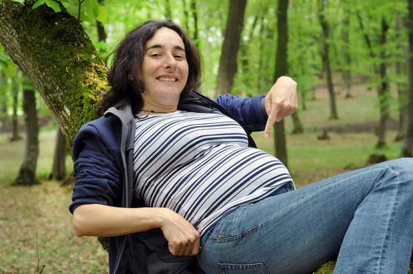 Mujer embarazada relajándose en un tronco de árbol — Foto de Stock