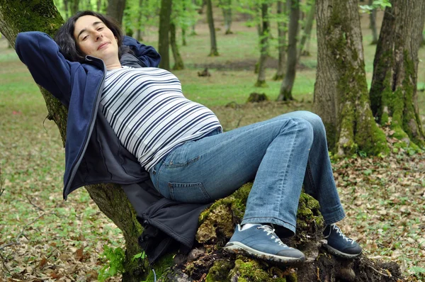 Hamile kadın bir ağaç gövdesinde rahatlatıcı — Stok fotoğraf