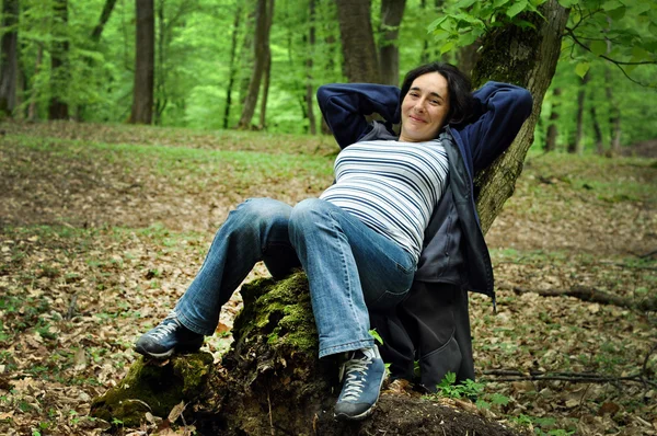 Вагітна жінка розслабляється на стовбурі дерева — стокове фото