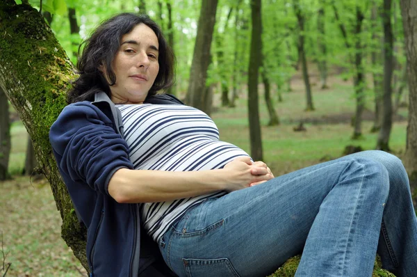 Mulher grávida relaxando em um tronco de árvore — Fotografia de Stock