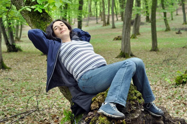 Mulher grávida relaxando em um tronco de árvore — Fotografia de Stock