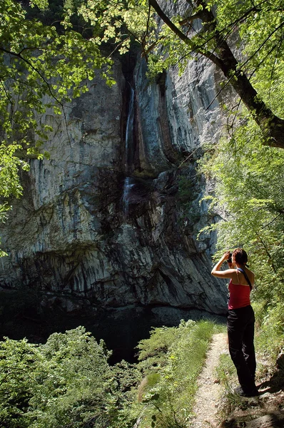 Trekking kvinna fotograferar ett vattenfall — Stockfoto