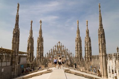 Milan, İtalya - 22 Ağustos 2021: Milano Duomo 'nun terasında yürüyen turistler, Gotik kuleler ve şehre bakan mermer detaylarla çevrili.