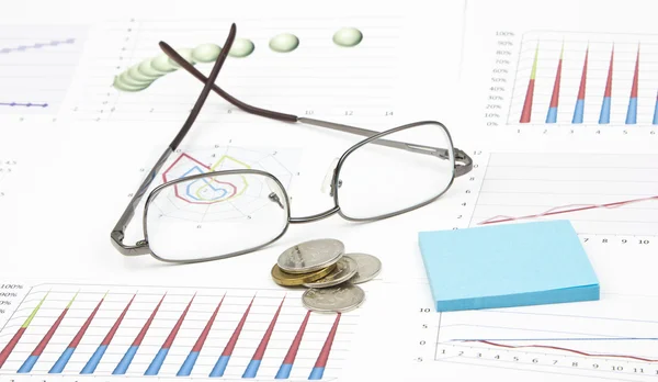 Business-stilleven van een grafiek, brillen, munten, sticker — Stockfoto