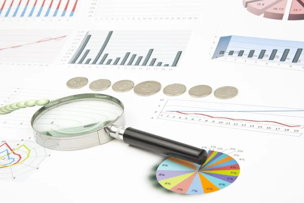 Business-stilleven van een diagram, Vergrootglas, munten Stockfoto