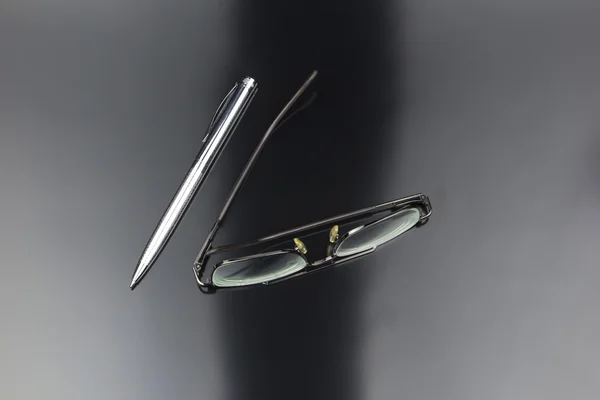 Natura morta d'affari di occhiali, penna lucente su materia plastica nera — Foto Stock