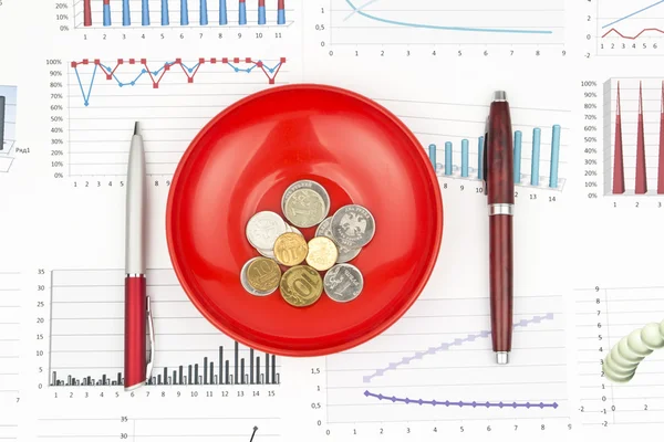 Natura morta d'affari di una penna due, diagramma, monete in un piatto — Foto Stock
