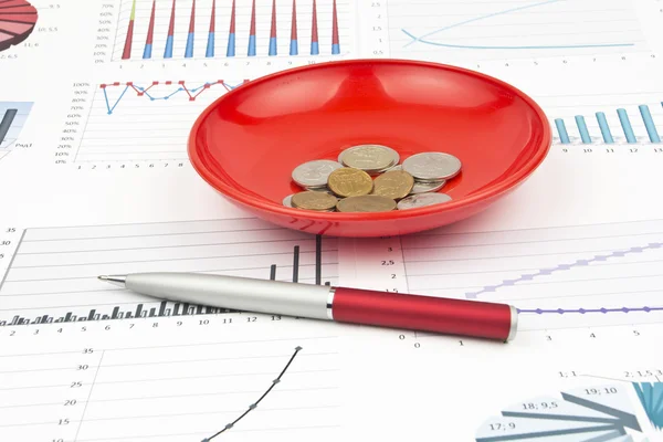 Business-stilleben av en penna, diagram, mynt i en tallrik — Stockfoto