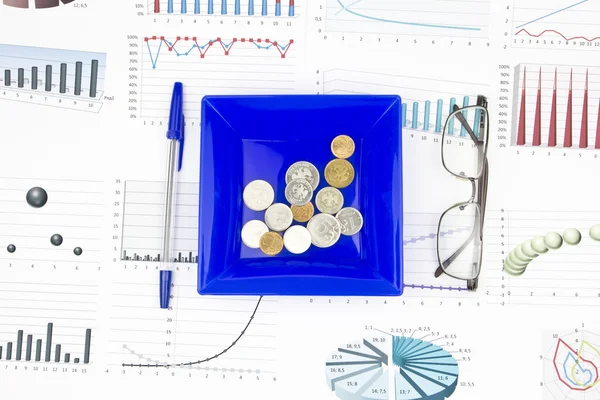 Bodegón de negocios de una pluma, anteojos, diagrama, monedas en un plato — Foto de Stock