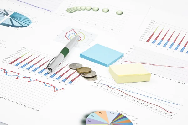 Business-stilleven van een groene pen, sticker, grafieken, munten — Stockfoto