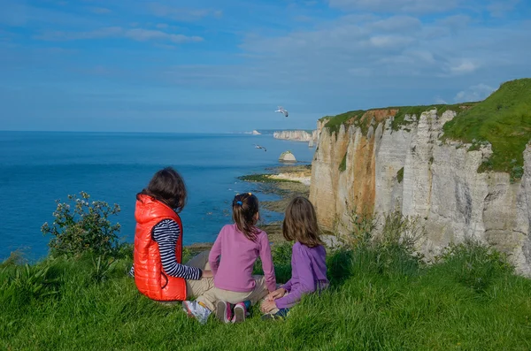 Moeder en kinderen kijken prachtig uitzicht op zee zittend op de rotsen, familie wandelen op vakantie in Frankrijk, Etretat — Stockfoto