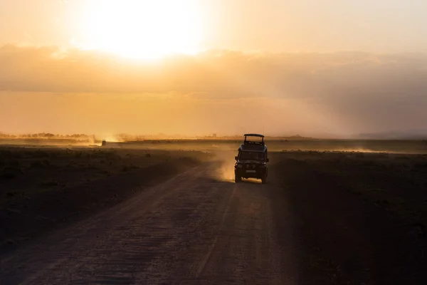 Ηλιοβασίλεμα στην αφρικανική σαβάνα, σιλουέτες των σαφάρι αυτοκίνητο και ζώα, την Αφρική, την Κένυα, Εθνικό Πάρκο Αμποσέλι — Φωτογραφία Αρχείου
