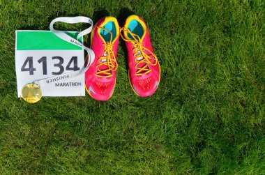 Koşu ayakkabıları, maraton yarışı önlük (sayı) ve son işlemci madalya çim arka plan, spor, fitness ve sağlıklı yaşam konsepti üzerinde