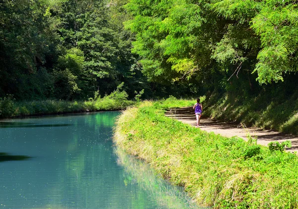 Corredor mulher ativa correndo perto do rio canal, ao ar livre correndo, esporte e conceito de estilo de vida saudável — Fotografia de Stock