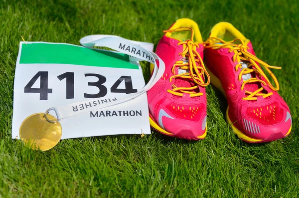 Laufschuhe, Marathonstartnummer und Finisher-Medaille auf Grashintergrund, Sport, Fitness und gesundem Lebensstil-Konzept — Stockfoto