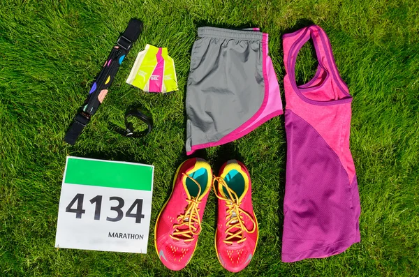 Löparskor, marathon race bib (nummer), löpare redskap och energi gel på gräs bakgrund, sport, fitness och hälsosam livsstilskoncept — Stockfoto