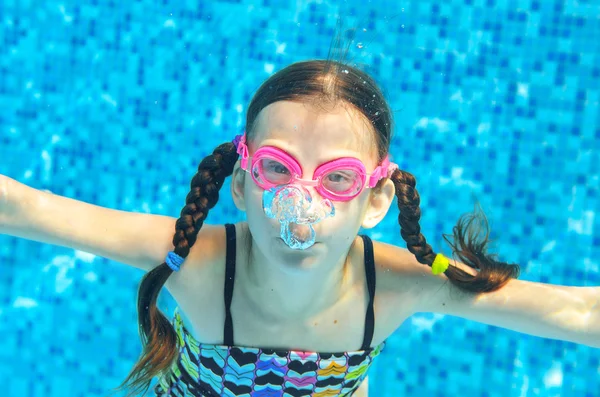 Criança nada na piscina subaquática, engraçado menina feliz em óculos se diverte debaixo d 'água e faz bolhas, esporte infantil em férias em família — Fotografia de Stock