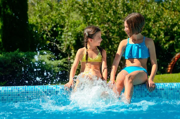 Fitness estivo, i bambini in piscina si divertono, le ragazze sorridenti schizzano in acqua, i bambini in vacanza in famiglia — Foto Stock