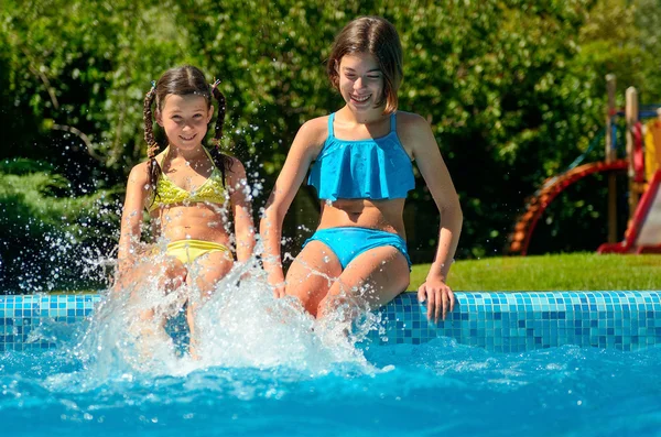 Fitness estivo, i bambini in piscina si divertono, le ragazze sorridenti schizzano in acqua, i bambini in vacanza in famiglia — Foto Stock