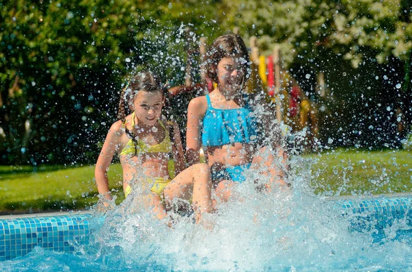 I bambini in piscina si divertono e schizzano in acqua, i bambini in vacanza in famiglia — Foto Stock