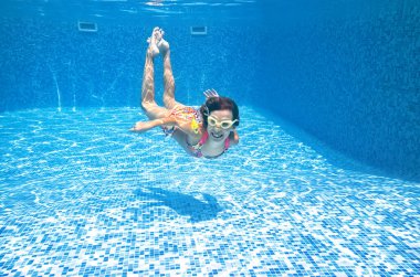 Çocuk yüzme havuzunda su altında yüzüyor, küçük aktif kız suya dalıyor ve su altında eğleniyor, çocuk fitness ve aile tatilinde spor yapıyor. 