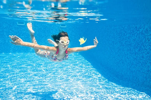 子供はスイミングプールで水中で泳ぎ 小さなアクティブな女の子はダイビングし 家族の休暇で水 子供のフィットネスやスポーツの下で楽しみを持っています — ストック写真