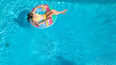 Havuz havuzu manzaralı aktif bir kız, çocuk şişme yüzükle yüzüyor, çocuk aile tatilinde mavi suda eğleniyor.