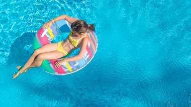 Havuz havuzu manzaralı aktif bir kız, çocuk şişme yüzükle yüzüyor, çocuk aile tatilinde mavi suda eğleniyor.