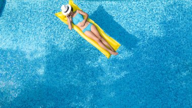 Yüzme havuzunda dinlenen güzel bir genç kız, şişme yatakta yüzen ve aile tatilinde suda eğlenen bir kadın, tropikal tatil beldesi, yukarıdan drone manzarası