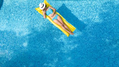 Yüzme havuzunda dinlenen güzel bir genç kız, şişme yatakta yüzen ve aile tatilinde suda eğlenen bir kadın, tropikal tatil beldesi, yukarıdan drone manzarası