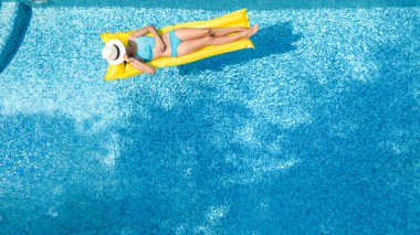 Yüzme havuzunda dinlenen güzel bir genç kız, şişme yatakta yüzen ve aile tatilinde suda eğlenen bir kadın, tropikal tatil beldesi, yukarıdan drone manzarası