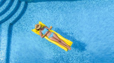 Yüzme havuzunda dinlenen güzel bir genç kız, şişme yatakta yüzen ve aile tatilinde suda eğlenen bir kadın, tropikal tatil beldesi, yukarıdan drone manzarası