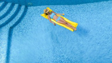 Yüzme havuzunda dinlenen güzel bir genç kız, şişme yatakta yüzen ve aile tatilinde suda eğlenen bir kadın, tropikal tatil beldesi, yukarıdan drone manzarası