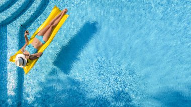 Yüzme havuzunda dinlenen güzel bir genç kız, şişme yatakta yüzen ve aile tatilinde suda eğlenen bir kadın, tropikal tatil beldesi, yukarıdan drone manzarası
