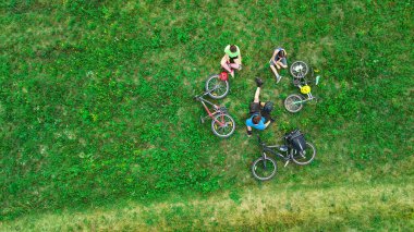 Yukardan bisikletli aile hava manzaralı, çocuklu mutlu aktif aile çim, aile sporu ve hafta sonları spor yapıyor.