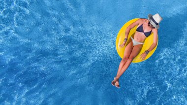 Havuz manzaralı şapkalı güzel bir kadın. Genç kız dinleniyor ve tatilde şişme yüzükle eğleniyor.