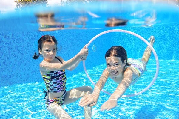 Niños activos felices nadan en la piscina y juegan bajo el agua — Foto de Stock