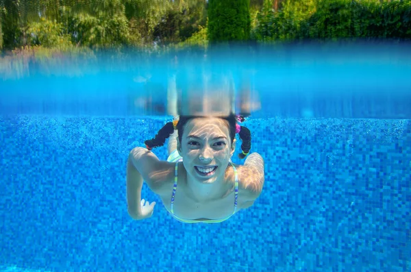 Ребенок плавает в бассейне, играет и веселится, под водой и над видом — стоковое фото