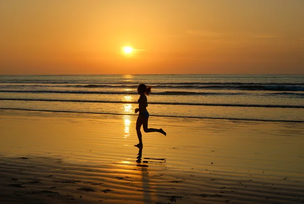 Silhueta de mulher corredor correndo na praia pôr do sol — Fotografia de Stock