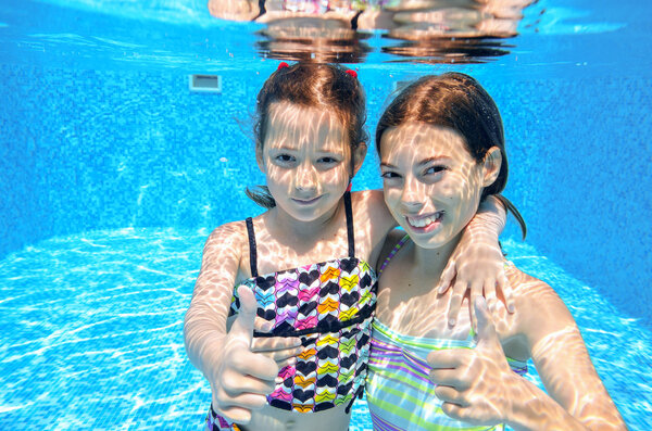 Kids swim in pool underwater, girls swimming