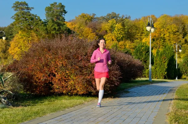 Frau läuft im Herbstpark, schöne Läuferin joggt im Freien — Stockfoto