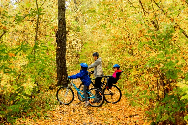 Famille à vélo dans le parc d'automne, père et enfants à vélo — Photo