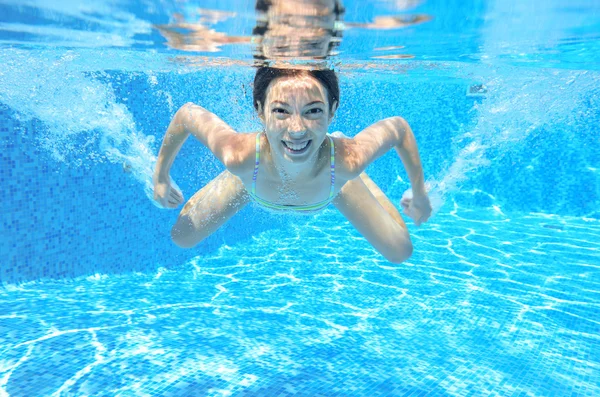 Chica feliz nada en la piscina bajo el agua, niño activo nadando —  Fotos de Stock