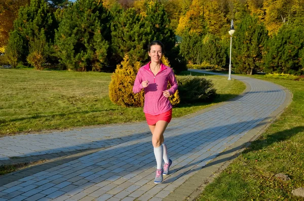 Frau läuft im Herbstpark, schöne Läuferin joggt im Freien — Stockfoto