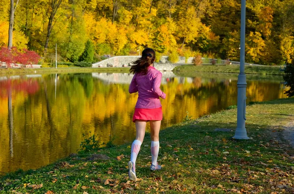 Frau läuft im Herbstpark, schöne Läuferin joggt im Freien — Stockfoto