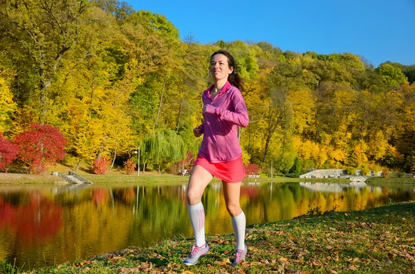 Frau läuft im Herbstpark, schöne Läuferin joggt im Freien — Stockfoto