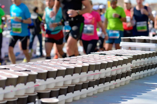 Maratona corrida de corrida, corredores na estrada, voluntário dando água e bebidas isotônicas — Fotografia de Stock