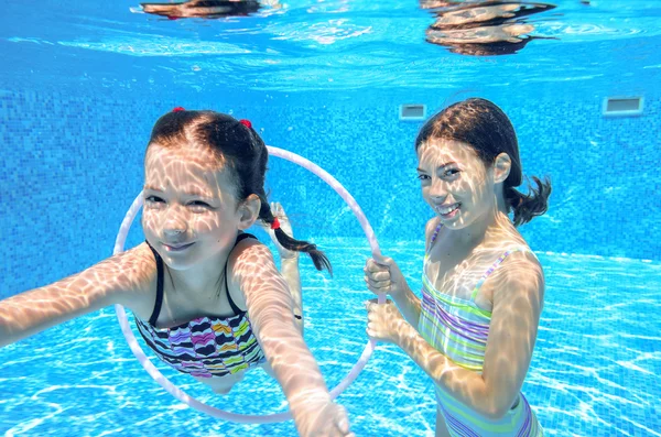 Niños felices nadan en la piscina bajo el agua, niñas nadando —  Fotos de Stock