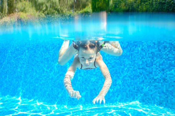 Menina feliz nada na piscina subaquática, criança ativa nadando — Fotografia de Stock