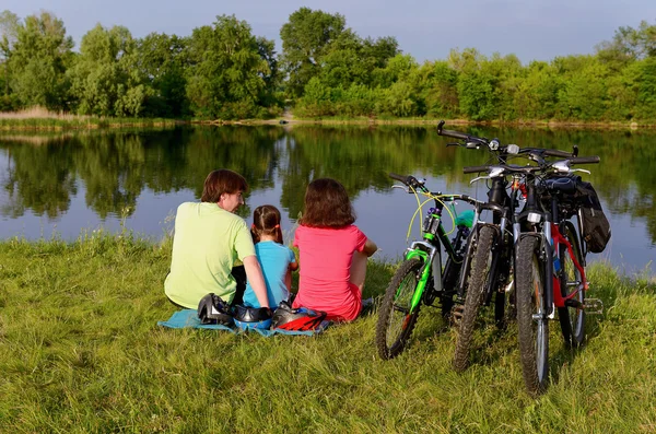 Paseo en bicicleta familiar al aire libre, padres activos y ciclismo infantil y relajarse cerca del hermoso río — Foto de Stock